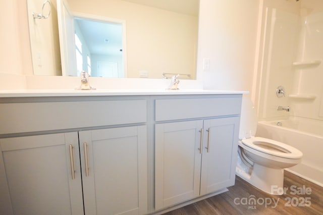 full bathroom with wood finished floors, vanity, washtub / shower combination, and toilet