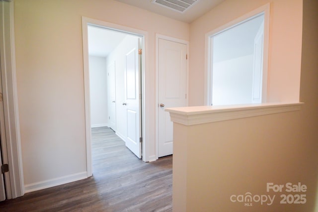 hallway with dark wood finished floors, baseboards, and visible vents