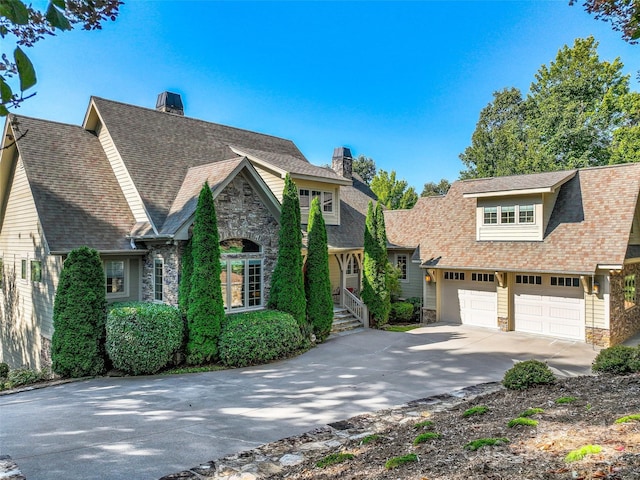 view of front of home with a chimney, a shingled roof, a garage, stone siding, and driveway