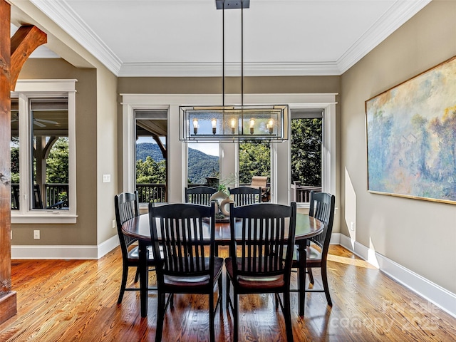 dining space with ornamental molding, a notable chandelier, baseboards, and wood finished floors