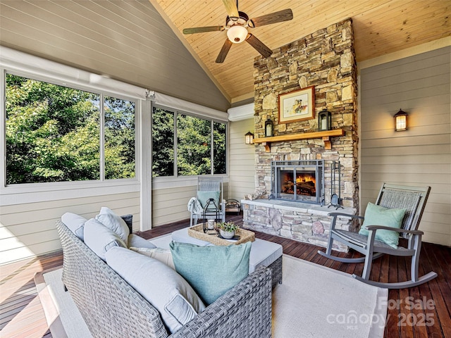 sunroom / solarium featuring wooden ceiling, vaulted ceiling, a stone fireplace, and ceiling fan