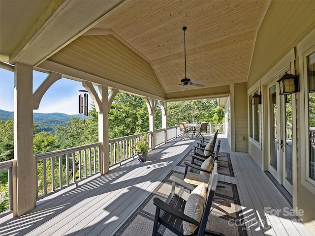 deck featuring a mountain view, outdoor dining area, and a ceiling fan