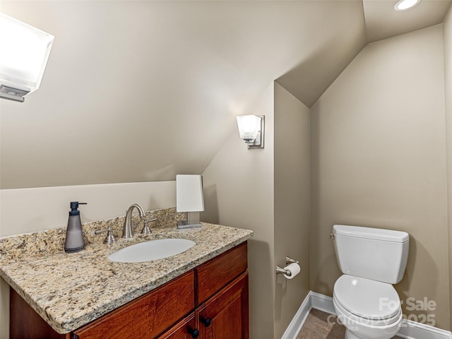 bathroom with lofted ceiling, vanity, toilet, and baseboards