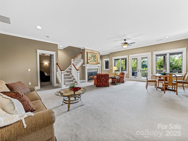 living room with light carpet, a glass covered fireplace, stairway, ornamental molding, and recessed lighting