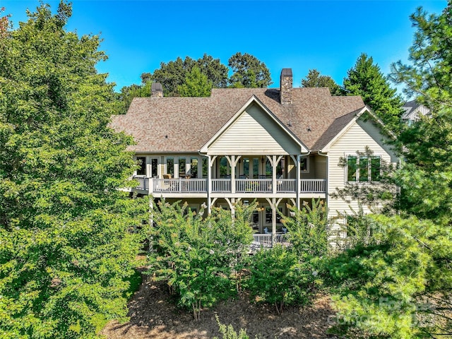 rear view of house featuring a shingled roof and a chimney