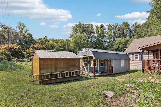 rear view of property featuring a yard, a porch, and a storage unit