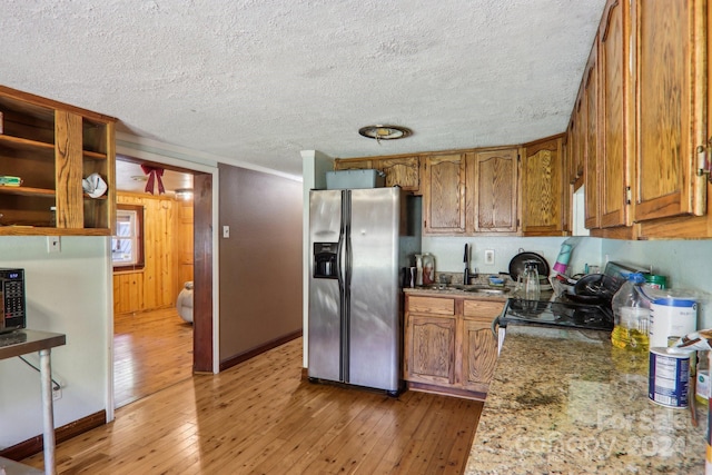 kitchen with black appliances, hardwood / wood-style flooring, dark stone counters, and a textured ceiling