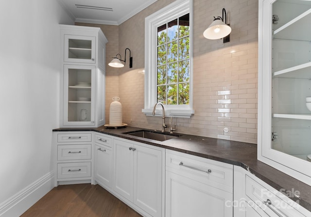 kitchen with backsplash, dark wood-type flooring, ornamental molding, sink, and white cabinetry
