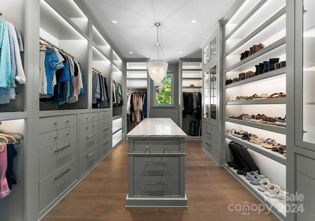 spacious closet featuring dark hardwood / wood-style flooring and a notable chandelier