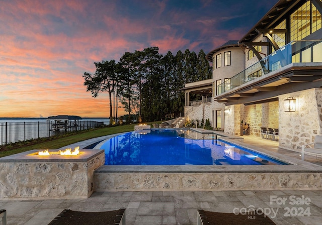 pool at dusk with a fire pit and a patio