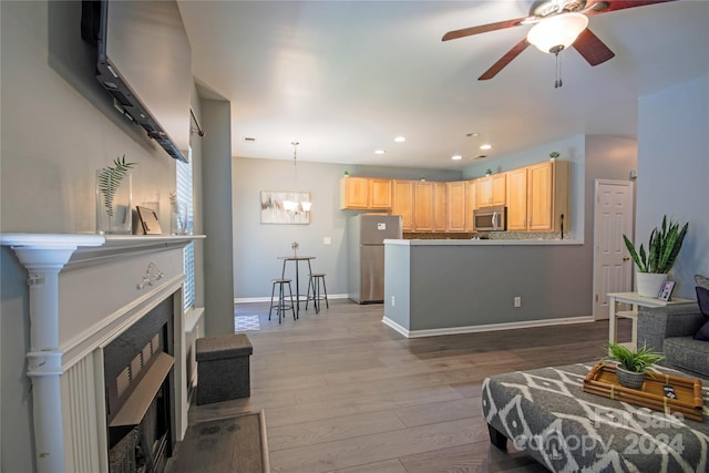 living room with light wood-type flooring and ceiling fan with notable chandelier