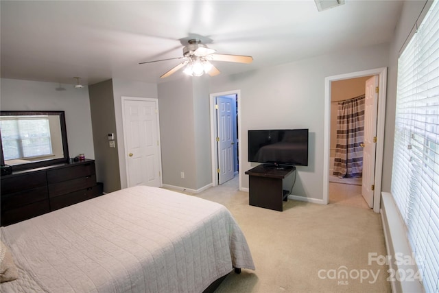 bedroom featuring ensuite bath, light carpet, and ceiling fan