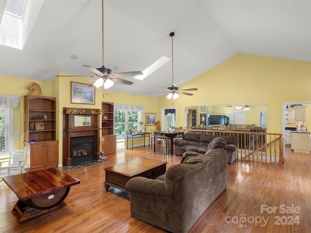 living room with a skylight, ceiling fan, and hardwood / wood-style flooring