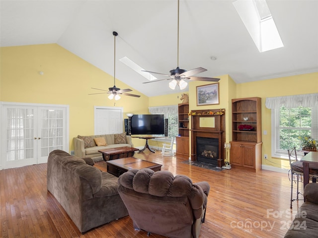 living room with ceiling fan, wood-type flooring, and a skylight