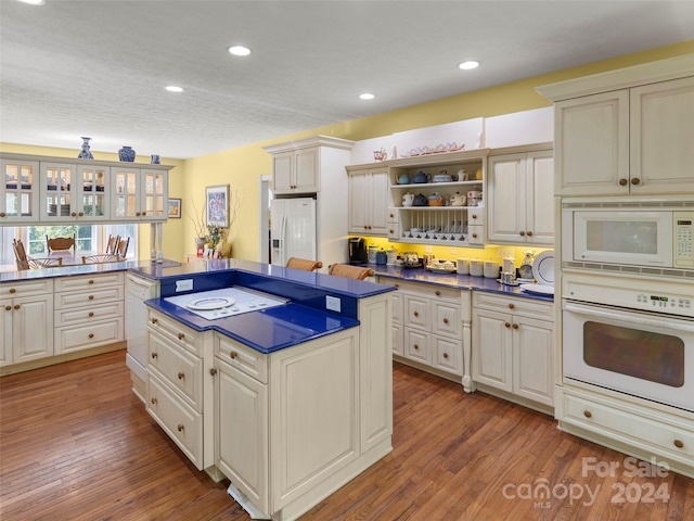 kitchen with a textured ceiling, a kitchen island, hardwood / wood-style floors, and white appliances