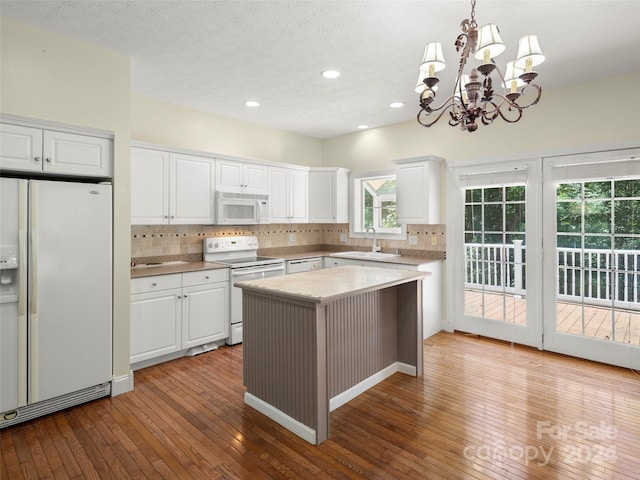 kitchen featuring white appliances, pendant lighting, a center island, white cabinetry, and light wood-type flooring