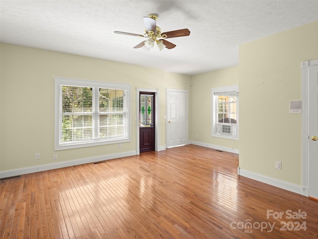 unfurnished living room featuring a textured ceiling, a healthy amount of sunlight, ceiling fan, and light hardwood / wood-style floors