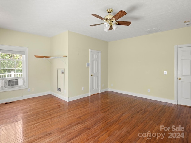 unfurnished living room with a textured ceiling, hardwood / wood-style flooring, cooling unit, and ceiling fan