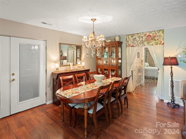 dining room with dark hardwood / wood-style floors, an inviting chandelier, and a textured ceiling