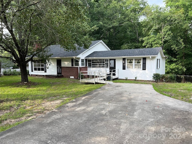 single story home featuring covered porch and a front yard