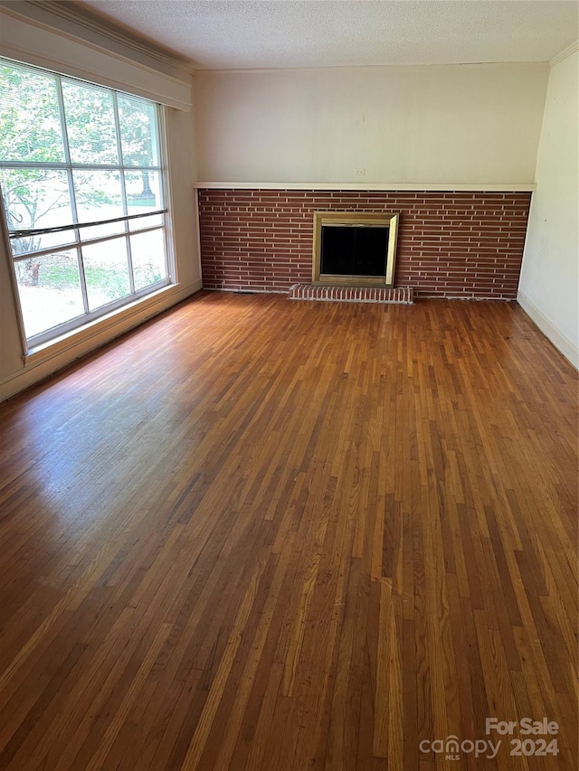 unfurnished living room with a fireplace, dark wood-type flooring, and a textured ceiling