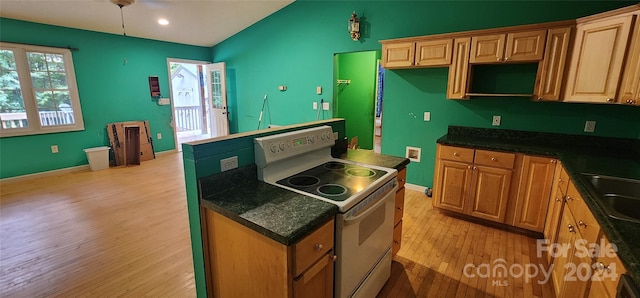 kitchen featuring electric range, light wood-type flooring, and dark stone counters