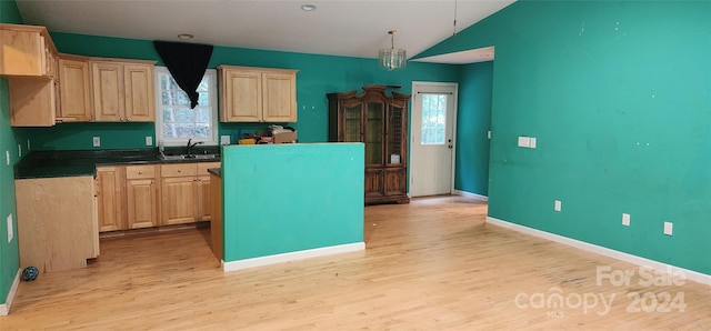 kitchen featuring vaulted ceiling, decorative light fixtures, light hardwood / wood-style flooring, light brown cabinetry, and sink