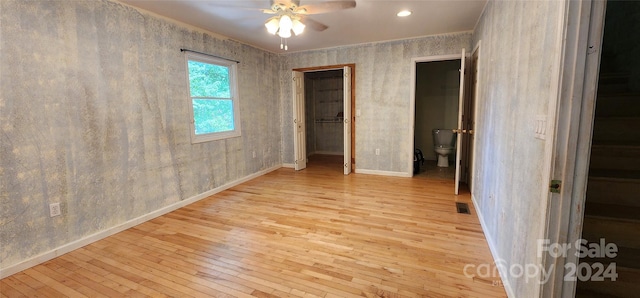 unfurnished bedroom featuring a walk in closet, ceiling fan, light hardwood / wood-style floors, and ensuite bath