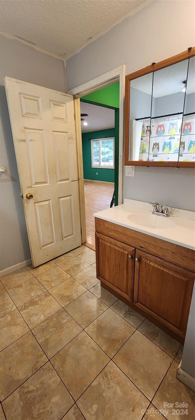 bathroom with vanity, a textured ceiling, and tile patterned flooring