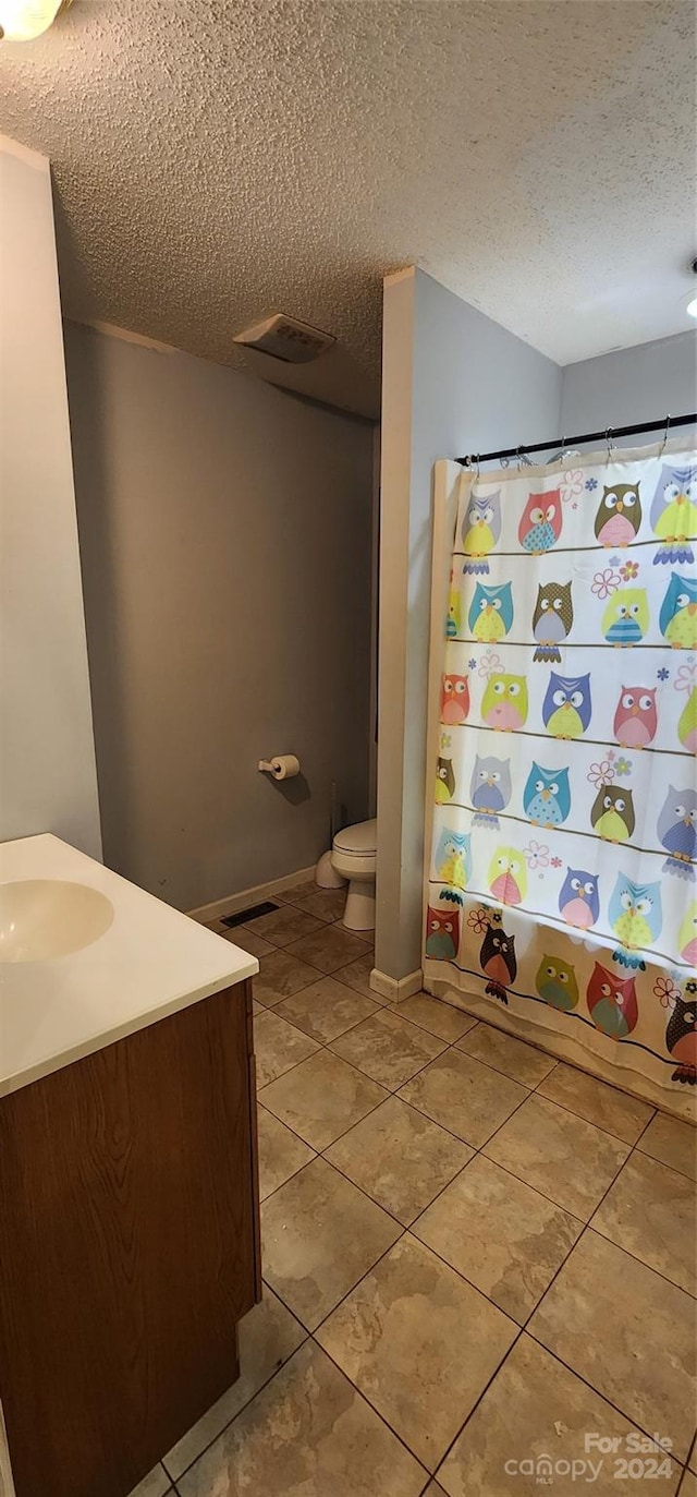 bathroom featuring a textured ceiling, vanity, toilet, and a shower with shower curtain