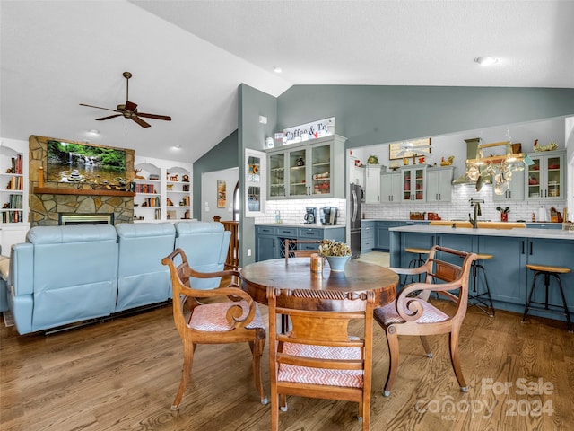 dining space featuring lofted ceiling, a stone fireplace, ceiling fan, and light hardwood / wood-style flooring