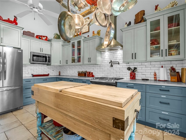 kitchen featuring hanging light fixtures, decorative backsplash, ceiling fan, and stainless steel appliances