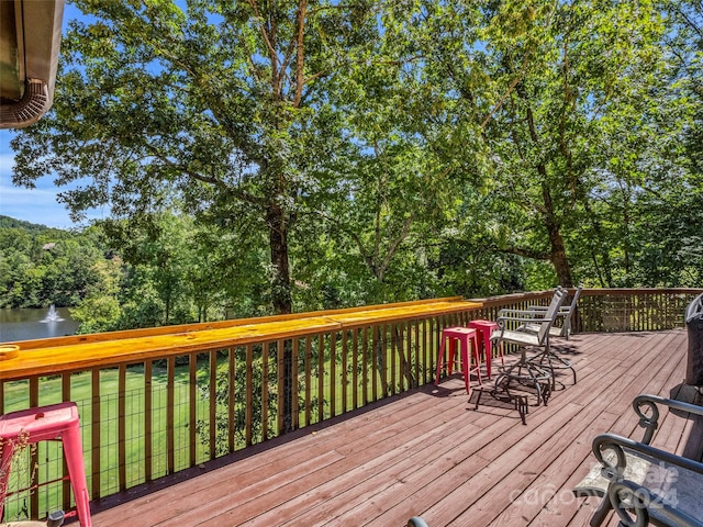 wooden terrace featuring a lawn and a water view