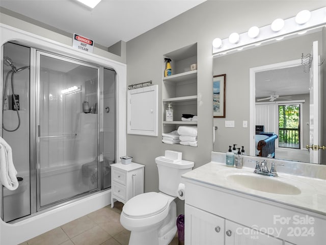 bathroom with ceiling fan, vanity, toilet, an enclosed shower, and tile patterned flooring