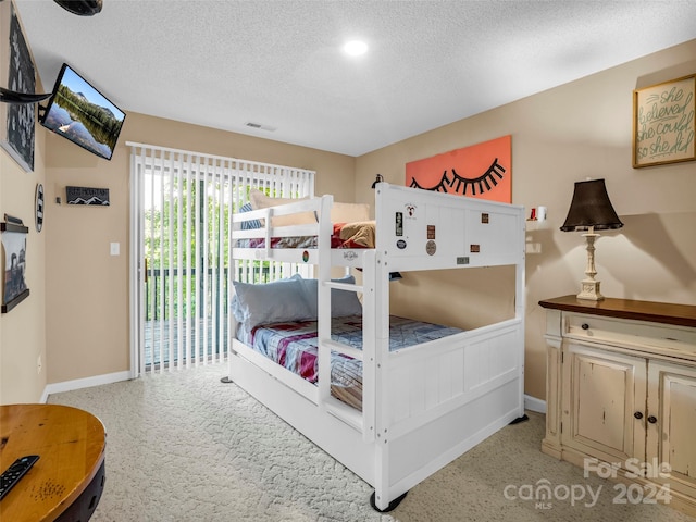 carpeted bedroom featuring a textured ceiling and access to exterior