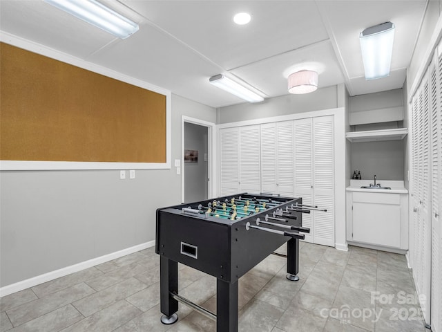 game room featuring light tile patterned floors, baseboards, and a sink