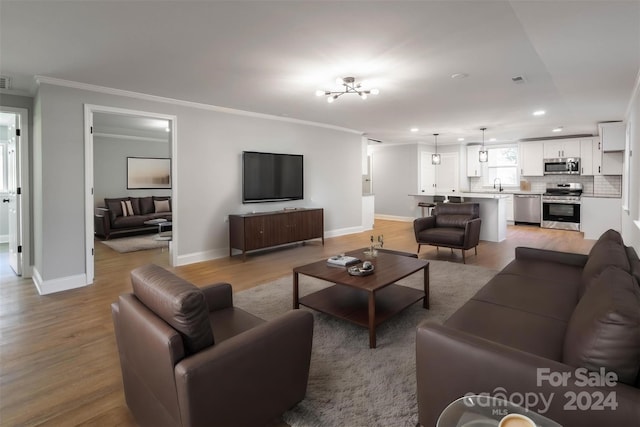 living area featuring baseboards, light wood finished floors, visible vents, recessed lighting, and crown molding