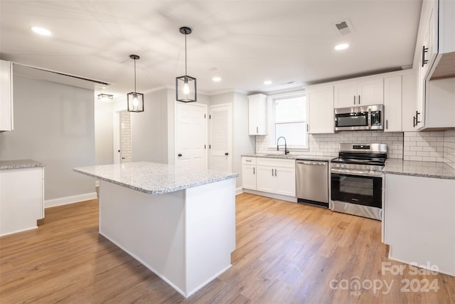 kitchen featuring light stone countertops, light hardwood / wood-style floors, stainless steel appliances, sink, and white cabinets