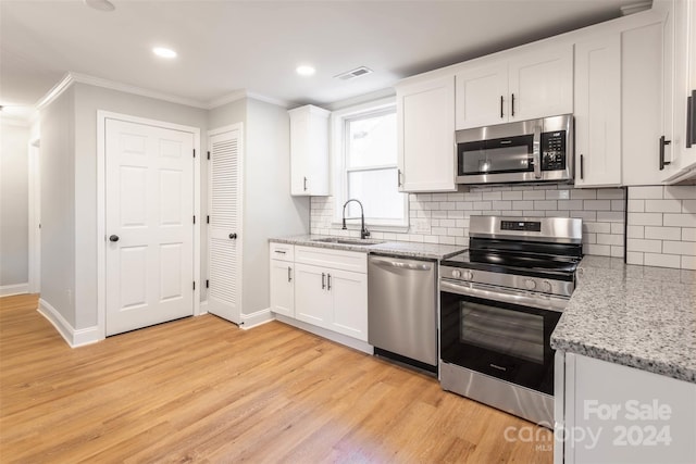 kitchen with light wood-type flooring, appliances with stainless steel finishes, white cabinetry, and sink