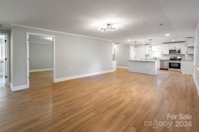 unfurnished living room featuring ornamental molding, sink, and light wood-type flooring