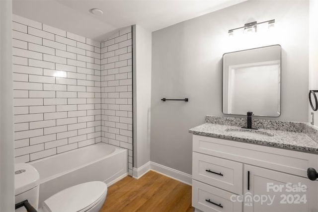 full bathroom with vanity, toilet, hardwood / wood-style flooring, and tiled shower / bath