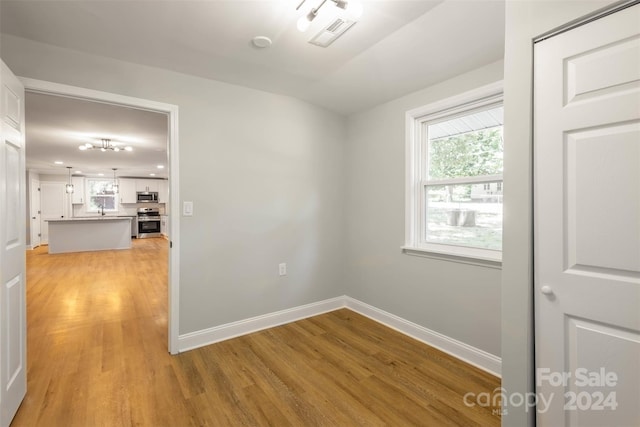 unfurnished room with an inviting chandelier and light hardwood / wood-style floors