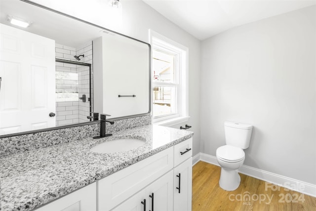 bathroom featuring vanity, toilet, hardwood / wood-style flooring, and a shower with door