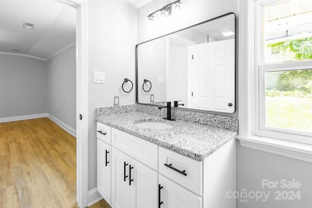 bathroom featuring hardwood / wood-style floors, vaulted ceiling, ornamental molding, and vanity