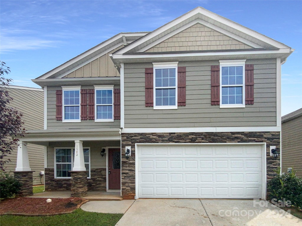 craftsman house with a garage, stone siding, a porch, and board and batten siding