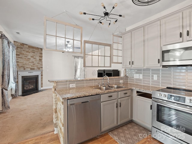 kitchen with stainless steel appliances, kitchen peninsula, sink, and decorative backsplash