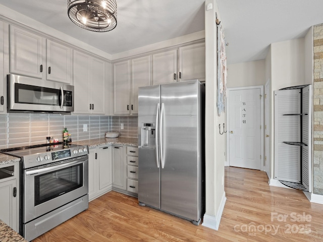 kitchen featuring light stone counters, decorative backsplash, stainless steel appliances, and light hardwood / wood-style floors