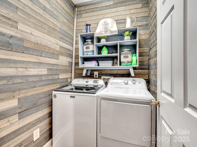 washroom featuring washing machine and dryer and wood walls