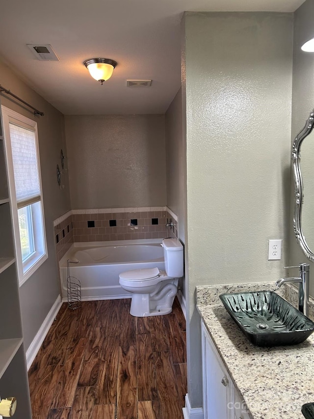 bathroom featuring vanity, toilet, hardwood / wood-style floors, and a washtub