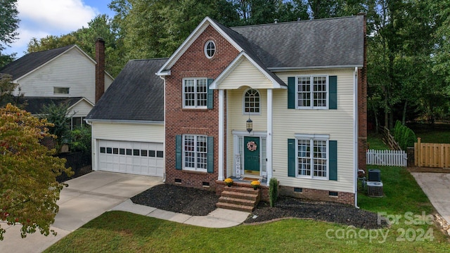 view of front of property featuring cooling unit, a garage, and a front yard